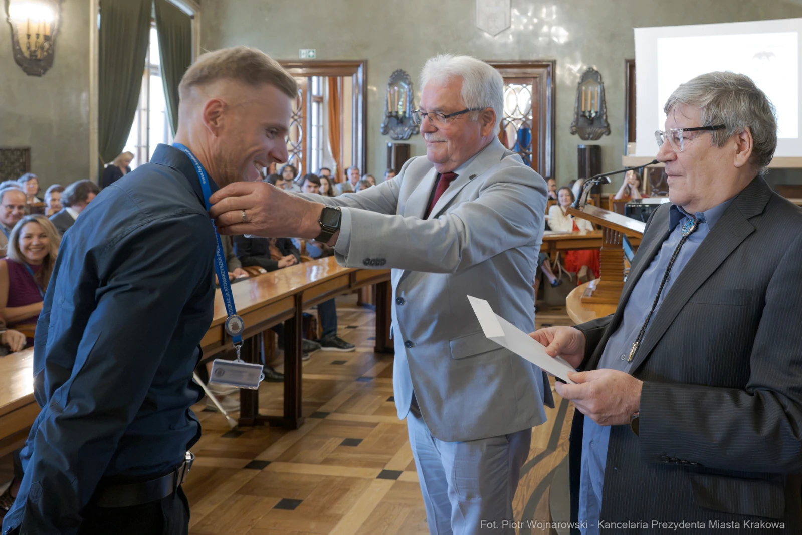 Mężczyzna odbiera medal podczas ceremonii wręczenia nagród w sali obrad.  Autor: Piotr Wojnarowski