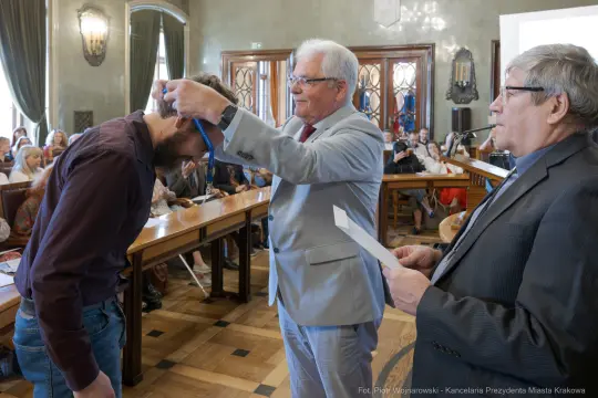 Wręczenie medalu podczas uroczystości w sali obrad.