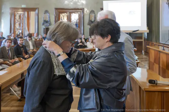 Ceremonia wręczenia odznaczenia w sali obrad z uczestnikami.