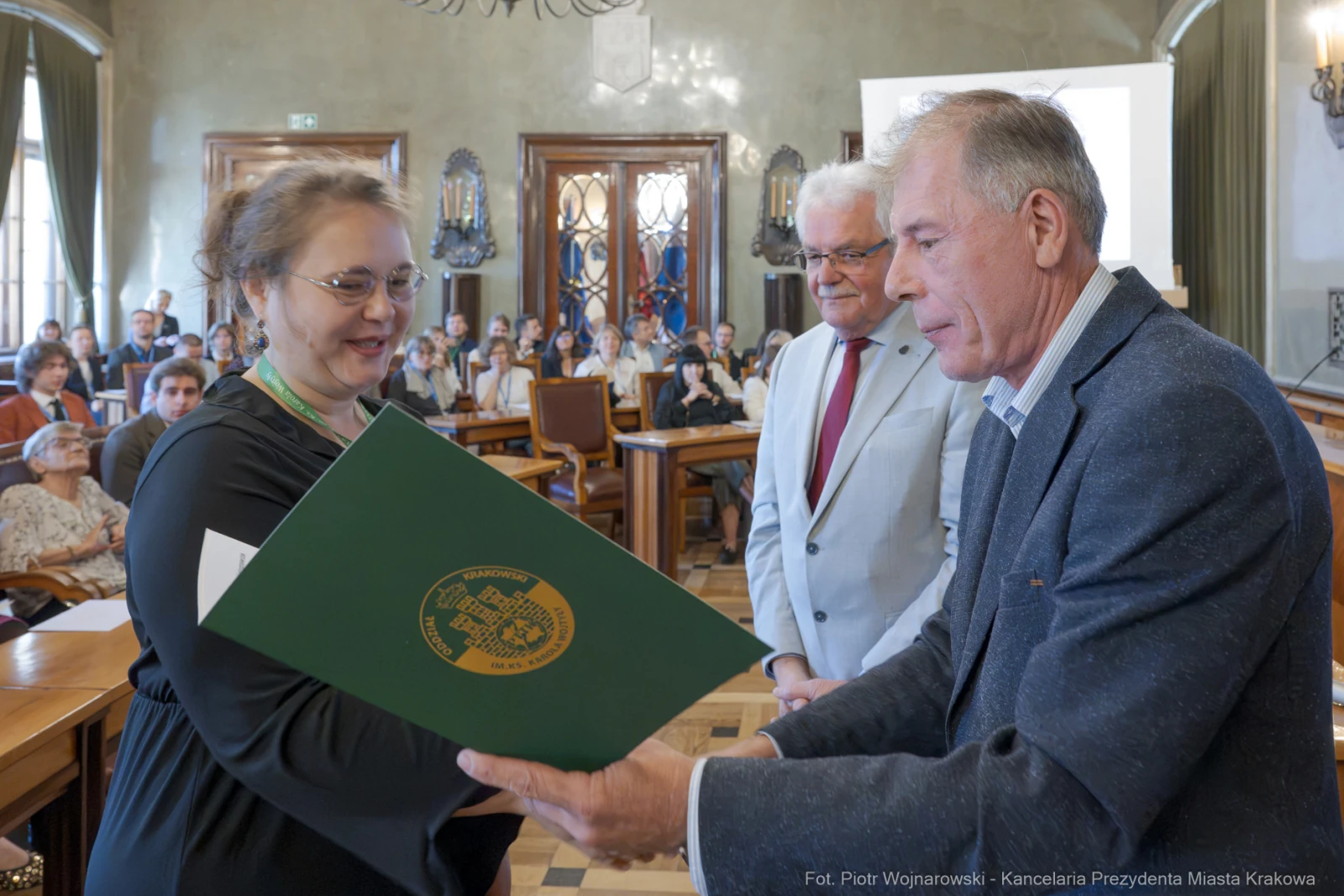 Wręczenie dyplomu w sali obrad z udziałem trzech osób.  Autor: Piotr Wojnarowski