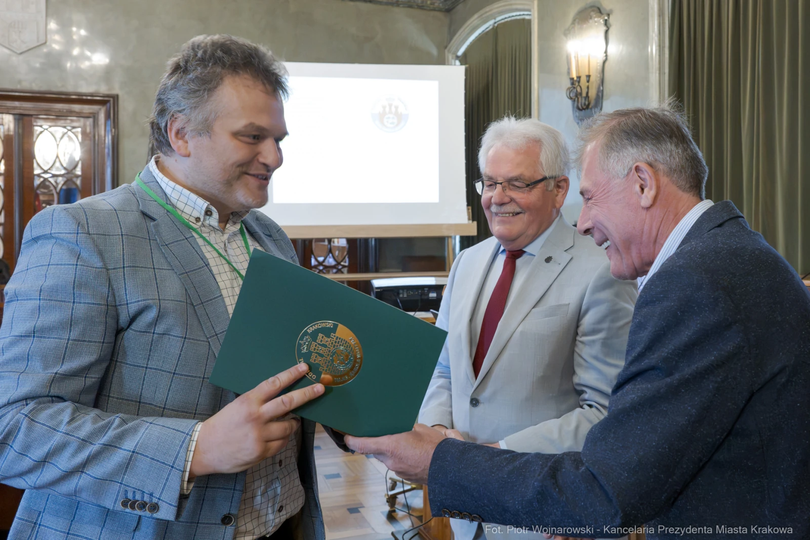 Wręczenie dyplomu w sali konferencyjnej, uśmiechnięci mężczyźni w formalnych strojach.  Autor: Piotr Wojnarowski
