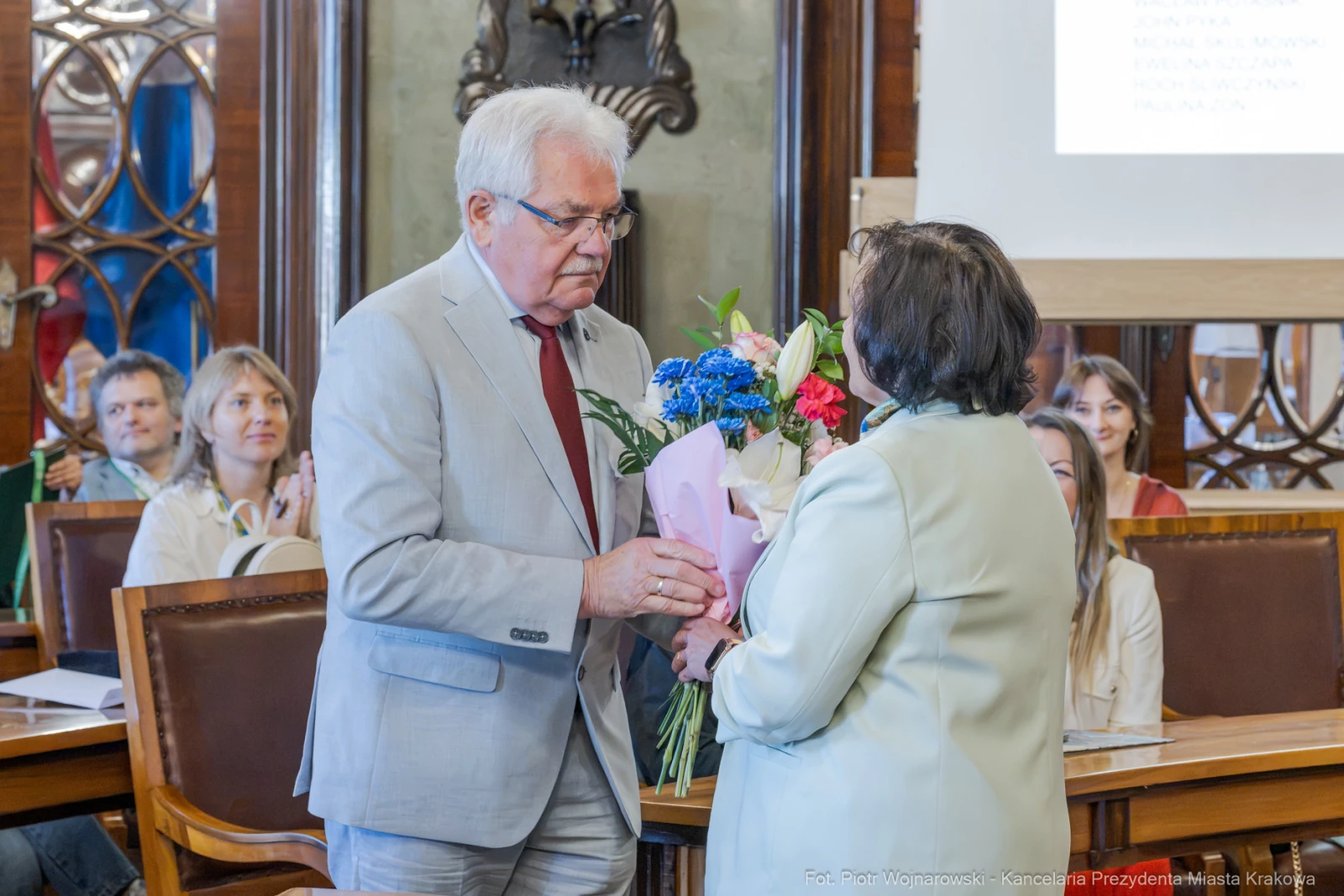 Mężczyzna wręcza bukiet kwiatów kobiecie w sali obrad.  Autor: Piotr Wojnarowski