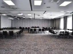 Pusta sala konferencyjna z okrągłymi stołami i krzesłami.