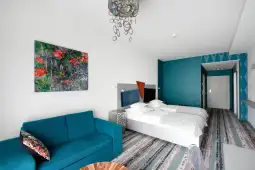 Nowoczesny pokój hotelowy z dwoma łóżkami, niebieskimi ścianami i kolorowym obrazem.