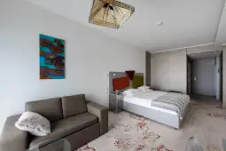 Nowoczesny pokój hotelowy z łóżkiem, sofą i dekoracyjnym oświetleniem.