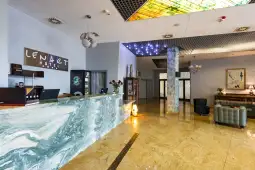 Recepcja hotelu z marmurowym blatem, eleganckim wystrojem i strefą wypoczynkową.