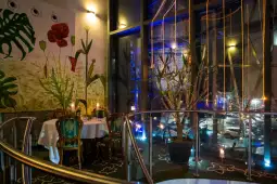 Elegancka restauracja z roślinnymi dekoracjami i świecami w nastrojowym oświetleniu.