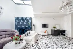 Nowoczesny salon z jasnymi ścianami, eleganckimi meblami i dekoracyjną podłogą.
