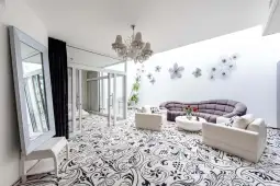 Nowoczesny salon z jasnymi ścianami, eleganckimi meblami i dekoracyjnym dywanem.
