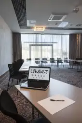 Laptop z napisem Lenart Hotel na stole w sali konferencyjnej.