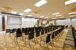 Pusty salon konferencyjny z rzędem krzeseł i ekranem prezentacyjnym.