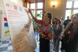 Kobieta prezentuje manifest kampanii wspierającej dzieciństwo bez przemocy.