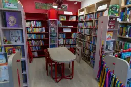 Nowoczesna biblioteka dziecięca z kolorowymi regałami i stolikiem do czytania.