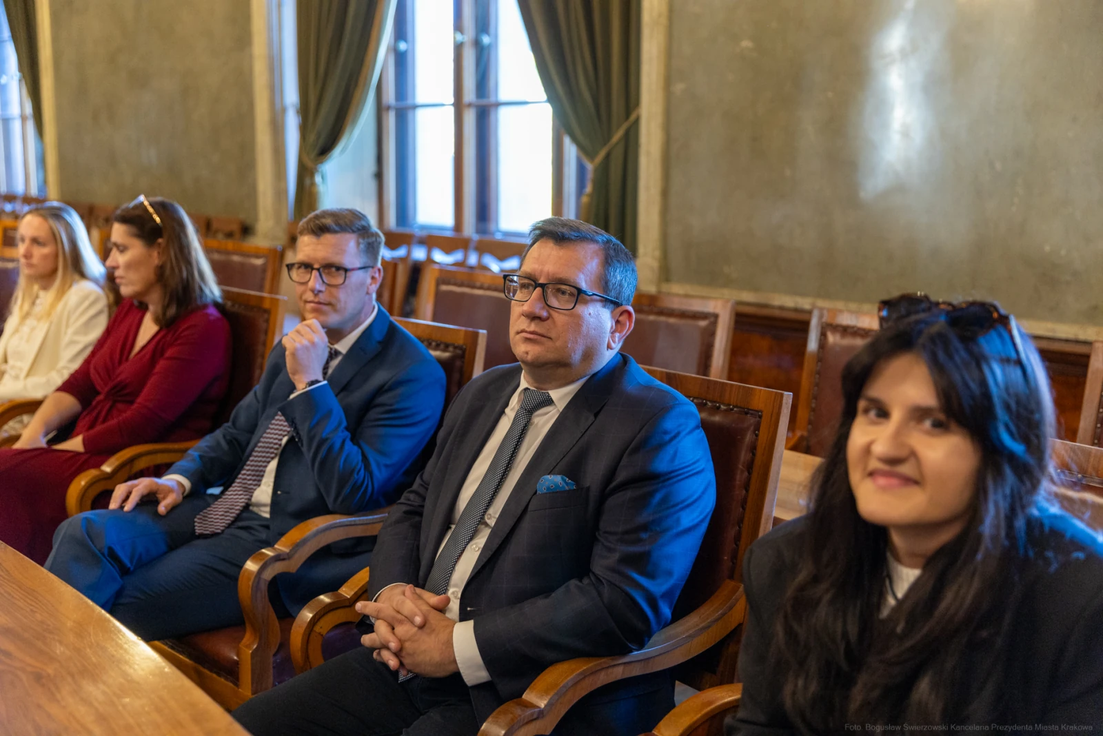 Grupa osób siedzących przy stole w sali z eleganckim wystrojem.  Autor: Bogusław Świerzowski