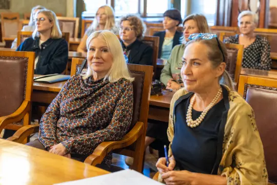 Kobiety siedzące w sali, uczestniczące w spotkaniu lub konferencji.