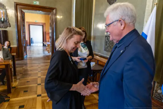 Uścisk dłoni między dwiema osobami w eleganckim wnętrzu.