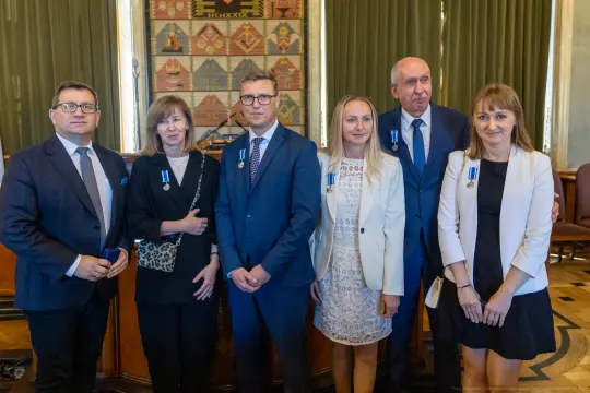 Grupa osób w formalnych strojach z odznaczeniami na piersiach.