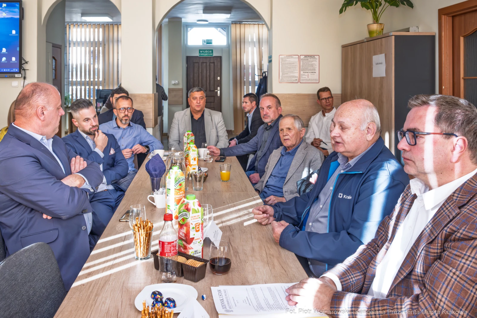Grupa mężczyzn w sali konferencyjnej, rozmawiających przy stole z napojami i przekąskami.  Autor: Piotr Wojnarowski