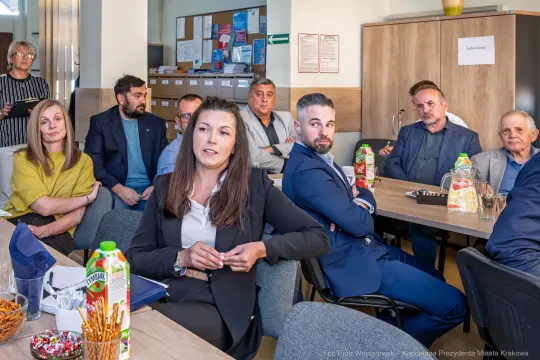 Spotkanie grupy ludzi w sali, z napojami i przekąskami na stole.