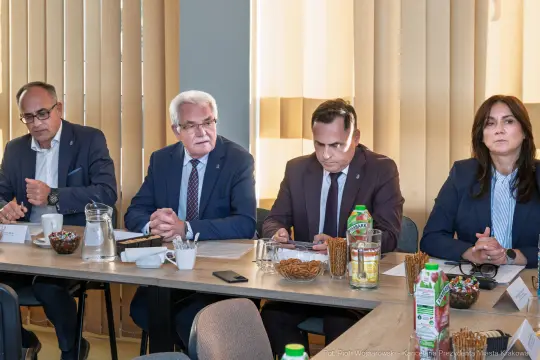 Czterech mężczyzn i jedna kobieta siedzą przy stole podczas spotkania.