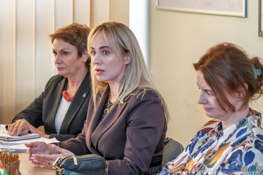 Trzy kobiety siedzą przy stole, prowadząc dyskusję w biurze.