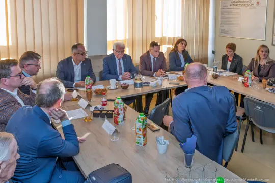 Spotkanie grupy ludzi przy stole, napoje i jedzenie na stole.