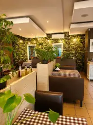 Nowoczesna restauracja z roślinami, brązowymi kanapami i stołami w kratkę.