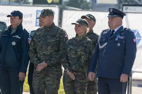 Grupa osób w mundurach wojskowych i policyjnych podczas ceremonii.
