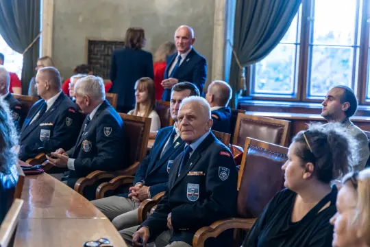 Grupa osób w mundurach siedzących przy stole w sali konferencyjnej.