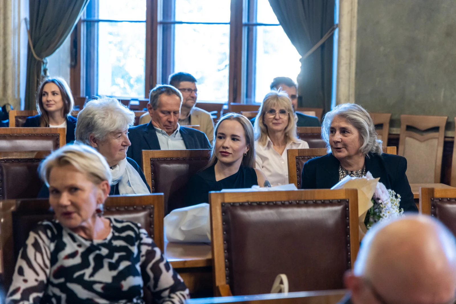 Grupa osób siedzących w sali, rozmawiających i uczestniczących w wydarzeniu.  Autor: Jan Graczyński