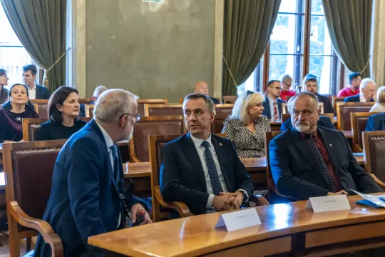 Spotkanie w sali obrad z uczestnikami siedzącymi przy stole.