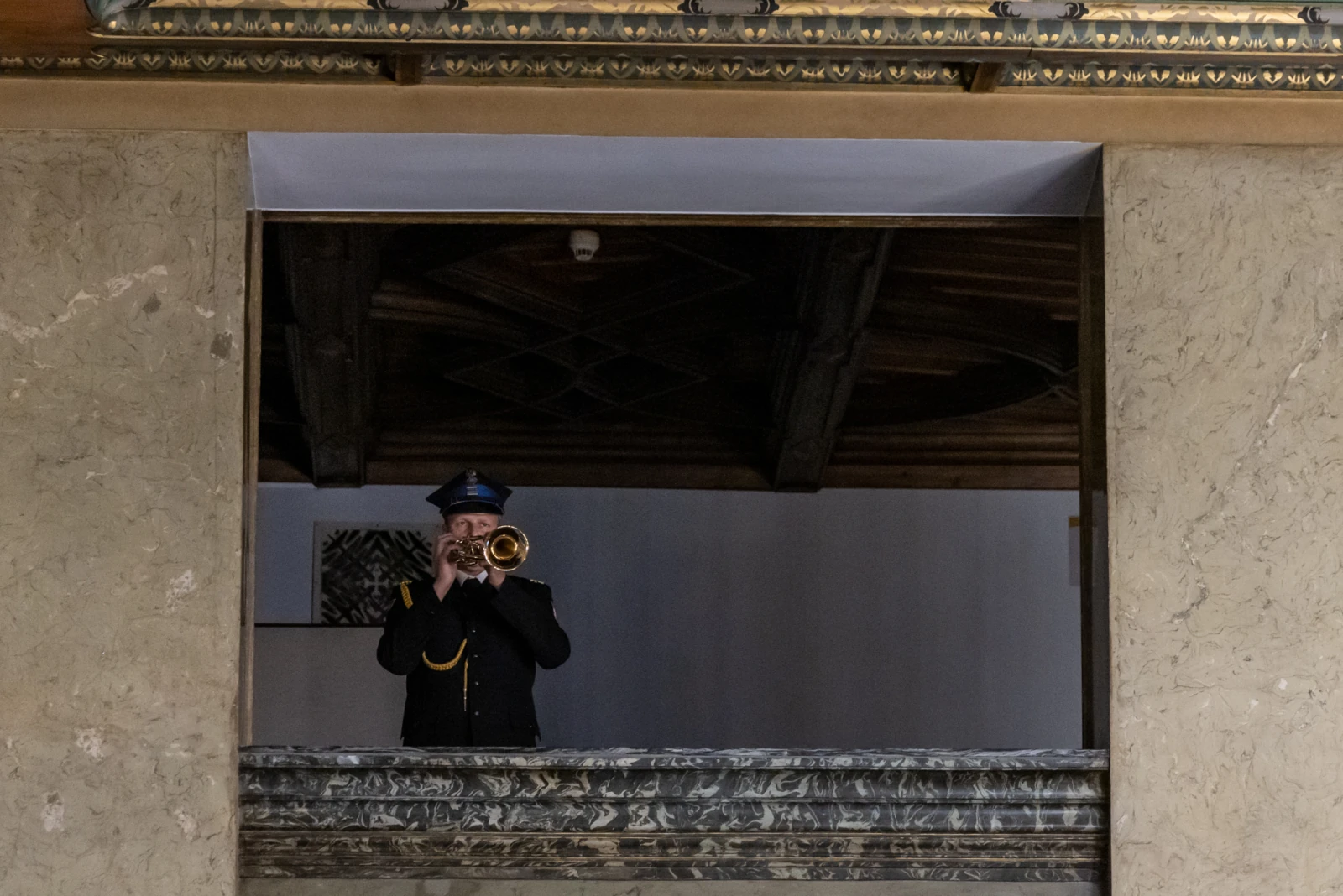 Mężczyzna w mundurze gra na trąbce z balkonu.  Autor: Jan Graczyński