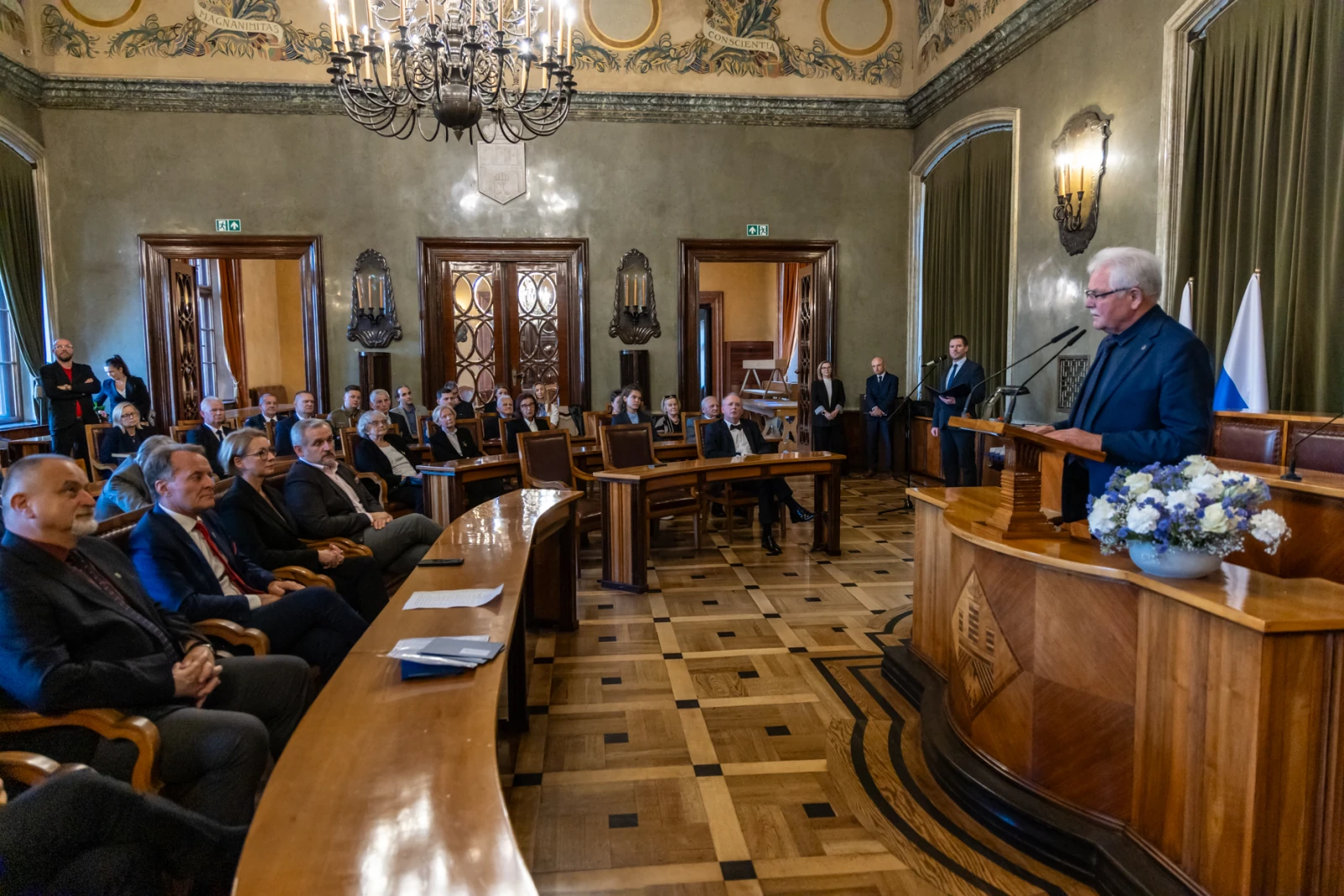 Spotkanie w eleganckiej sali, mężczyzna przemawia do zgromadzonych gości.  Autor: Jan Graczyński