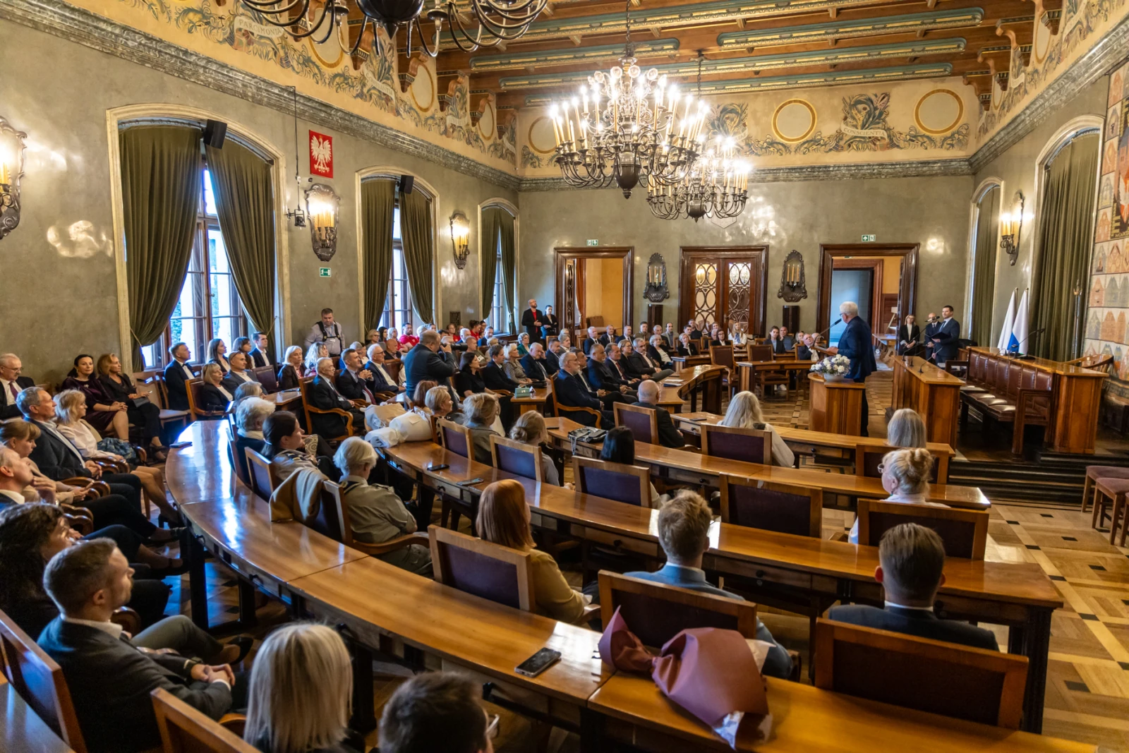 Spotkanie w sali obrad z uczestnikami siedzącymi przy długich stołach.  Autor: Jan Graczyński