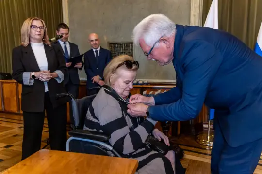 Uroczystość wręczenia odznaczenia kobiecie na wózku inwalidzkim.