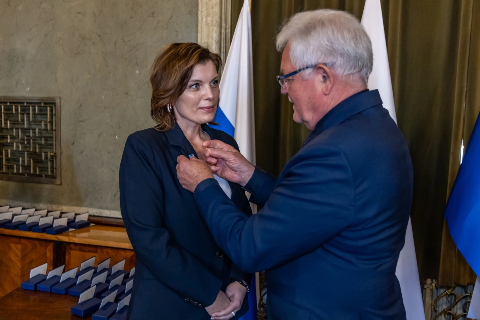 Wręczenie odznaczenia przez mężczyznę kobiecie w formalnym otoczeniu.  Autor: Jan Graczyński