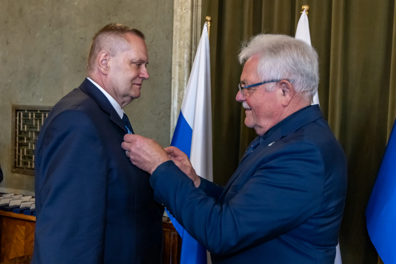 Uroczystość wręczenia odznaczenia mężczyźnie w garniturze.  Autor: Jan Graczyński