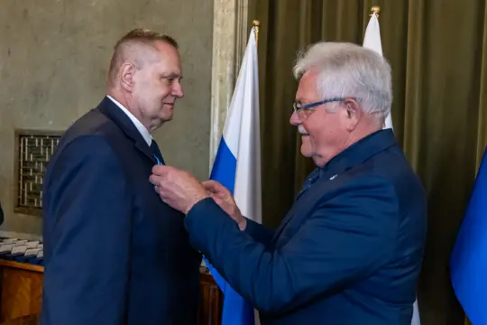 Uroczystość wręczenia odznaczenia mężczyźnie w garniturze.