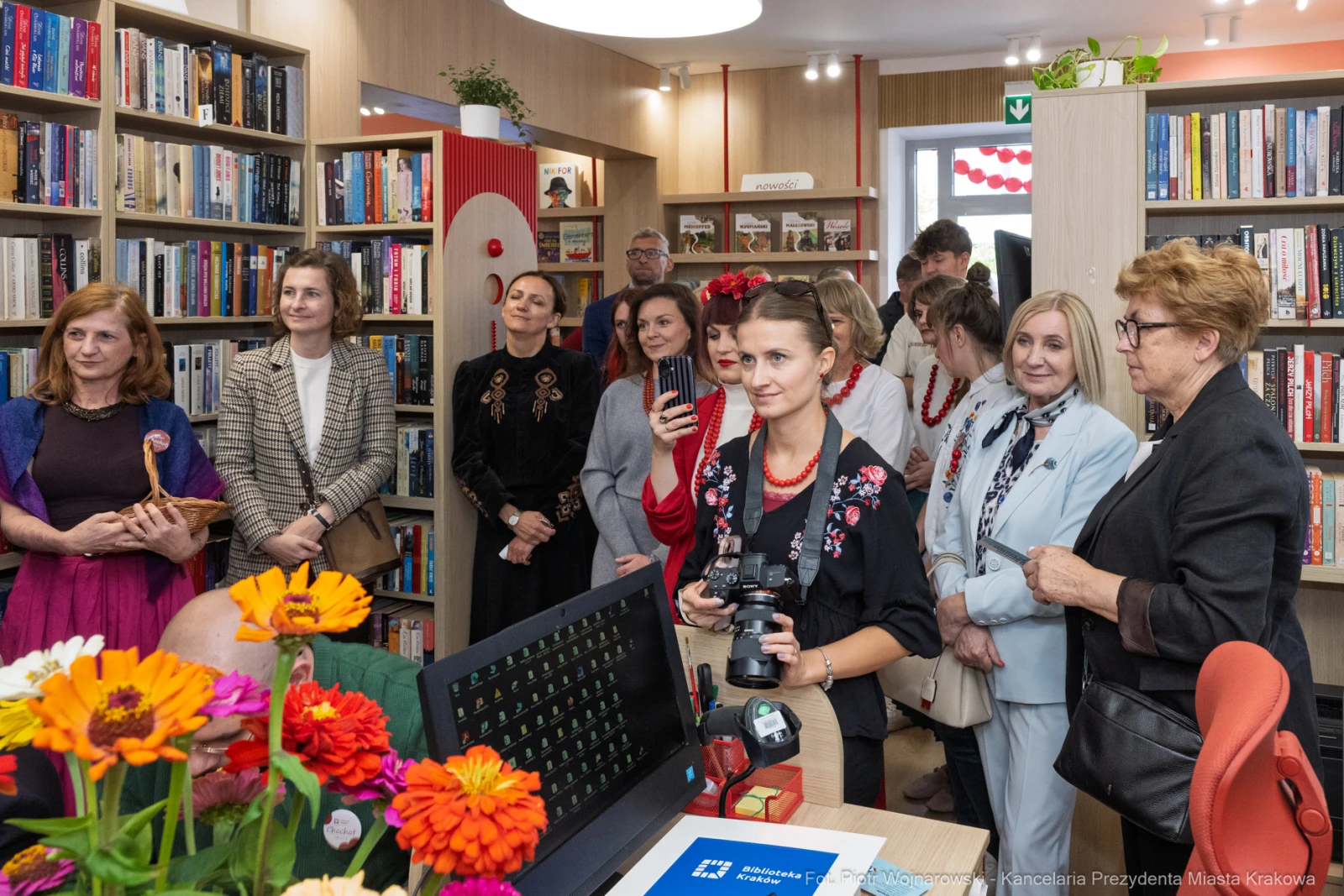 Grupa osób w bibliotece, niektóre w tradycyjnych strojach, podczas wydarzenia kulturalnego.  Autor: Piotr Wojnarowski