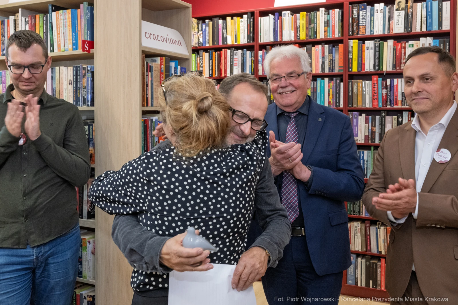 Uścisk dwóch osób w bibliotece, w tle regały z książkami. Obecni mężczyźni w garniturach.  Autor: Piotr Wojnarowski