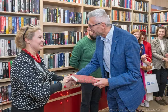 Wręczenie książki podczas wydarzenia literackiego w bibliotece.