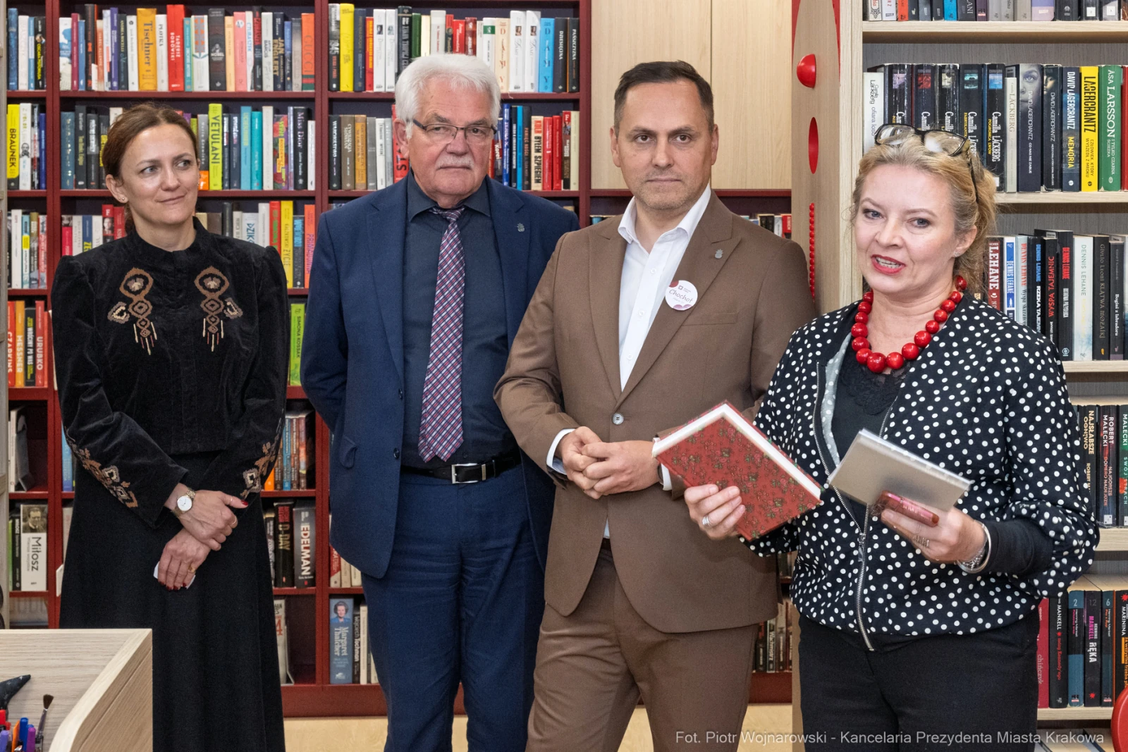 Cztery osoby w bibliotece, jedna z nich trzyma książki, wszyscy uśmiechnięci.  Autor: Piotr Wojnarowski