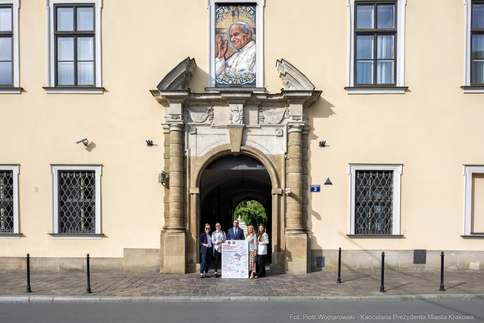 Grupa ludzi stojąca przy wejściu do budynku z mozaiką przedstawiającą papieża.  Autor: Piotr Wojnarowski