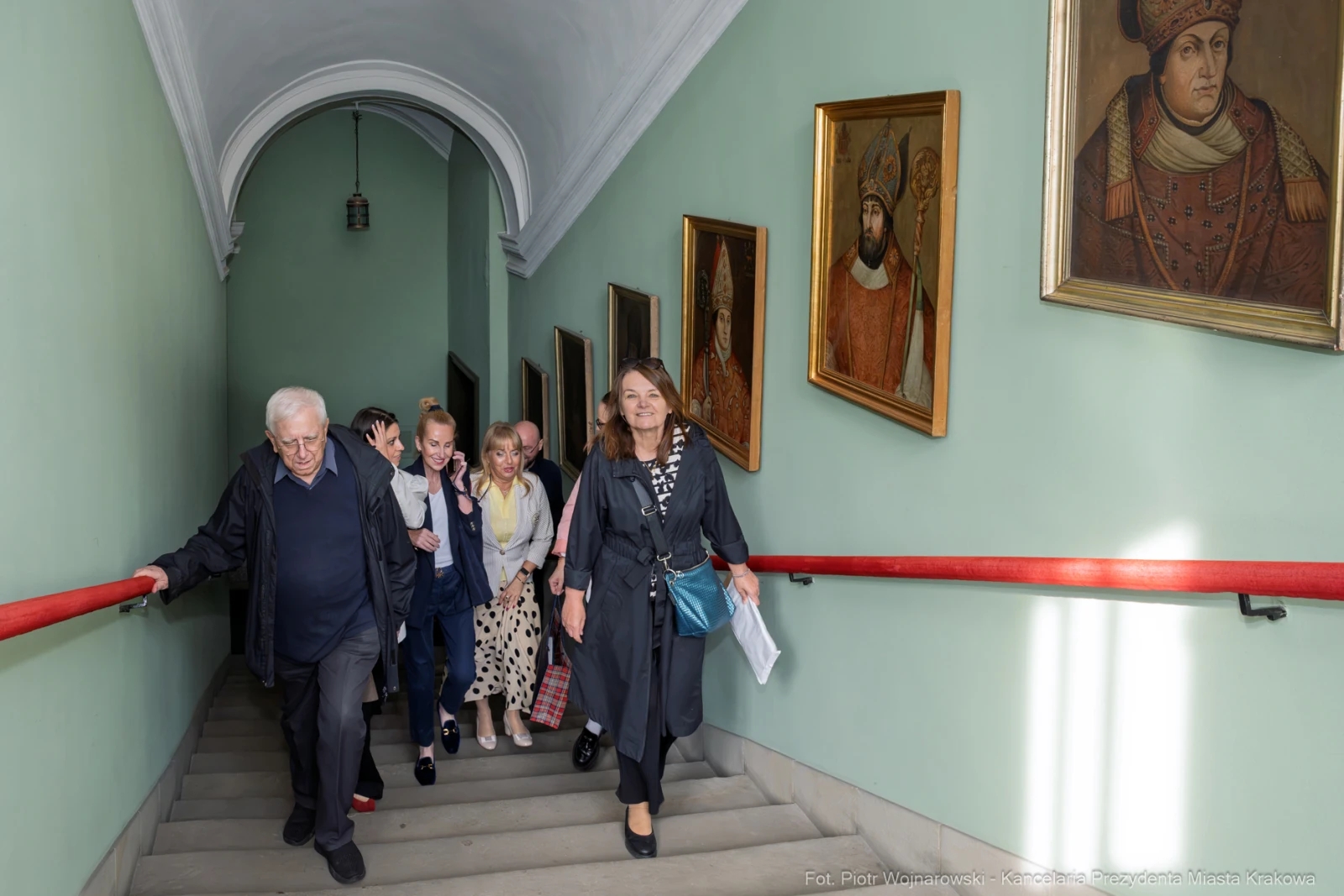 Grupa osób schodzących po schodach, w tle obrazy na ścianach.  Autor: Piotr Wojnarowski