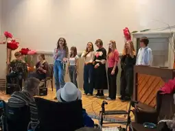 Młodzieżowy zespół wykonujący utwór muzyczny na scenie przed publicznością.