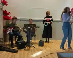 Młodzież grająca na instrumentach i śpiewająca podczas występu na scenie.
