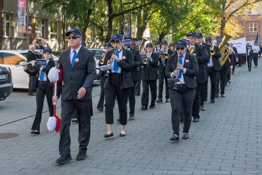 Grupa muzyków w mundurach grająca na ulicy podczas parady.