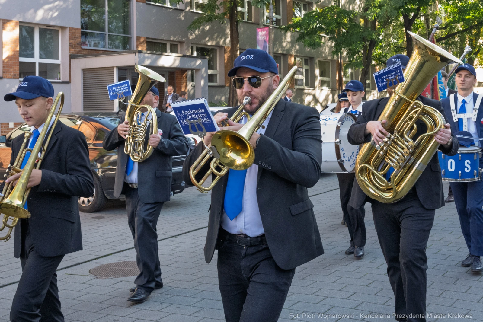 Muzycy w garniturach grają na instrumentach dętych podczas parady ulicznej.  Autor: Piotr Wojnarowski