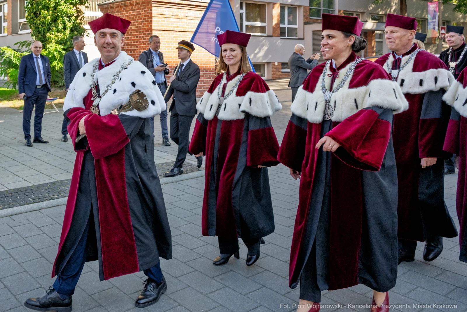Grupa osób w akademickich togach i biretach, idących w uroczystym pochodzie.  Autor: Piotr Wojnarowski