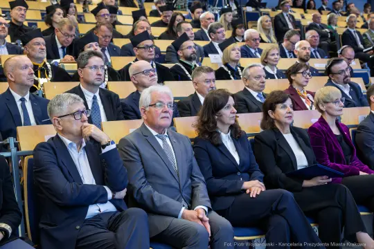 Grupa ludzi siedzących na widowni podczas wydarzenia formalnego.